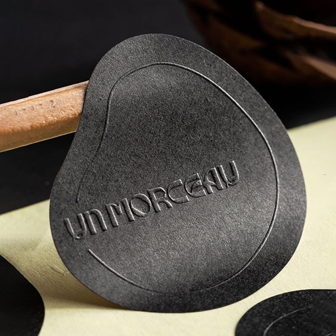 Custom die-cut embossed sticker on black textured stock — Pakvel