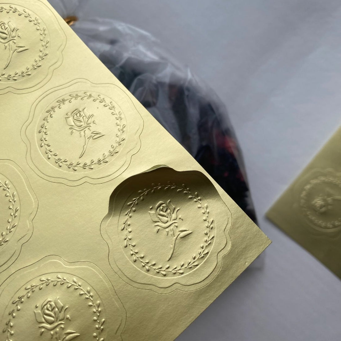Custom die-cut gold metallic sticker with an embossed floral crest and scalloped edge