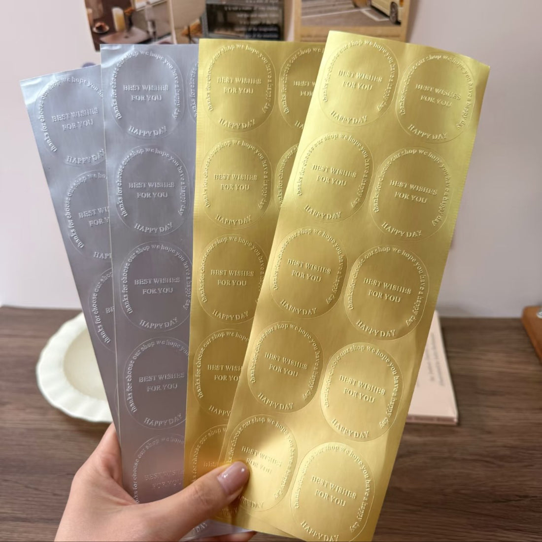 Hand holding gold and silver brushed metallic sticker strips with round labels, metallic finishes