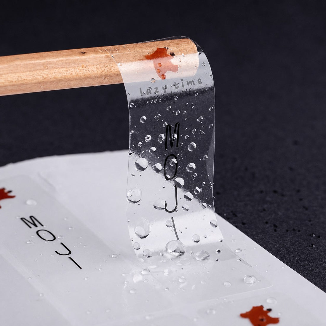 Clear waterproof sticker with minimal text design, water beading on transparent film