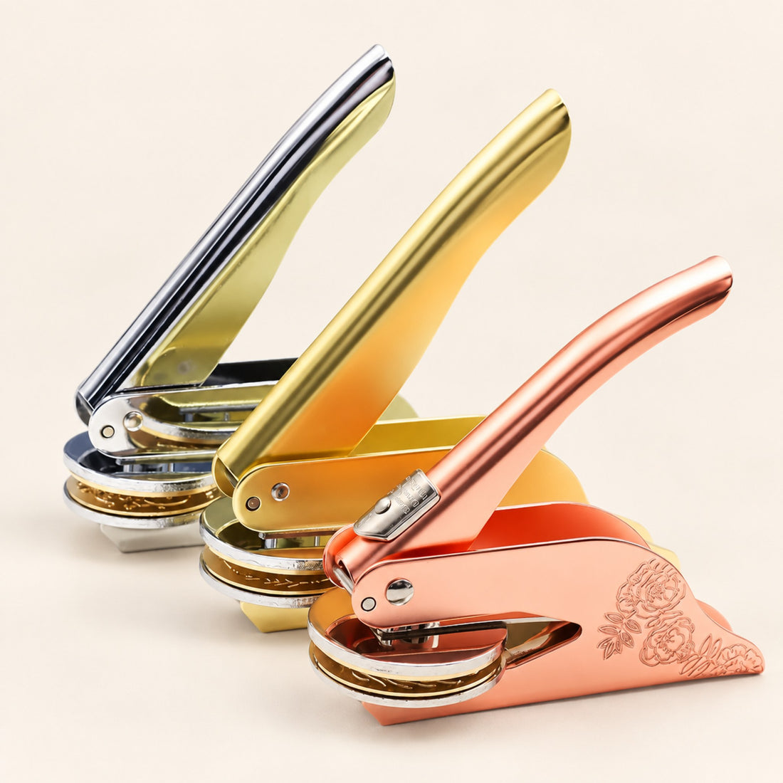 Five custom embossers lined up in gold, rose gold, silver, graphite and grey