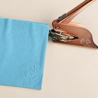 A blue paper napkin embossed with a monogram seal