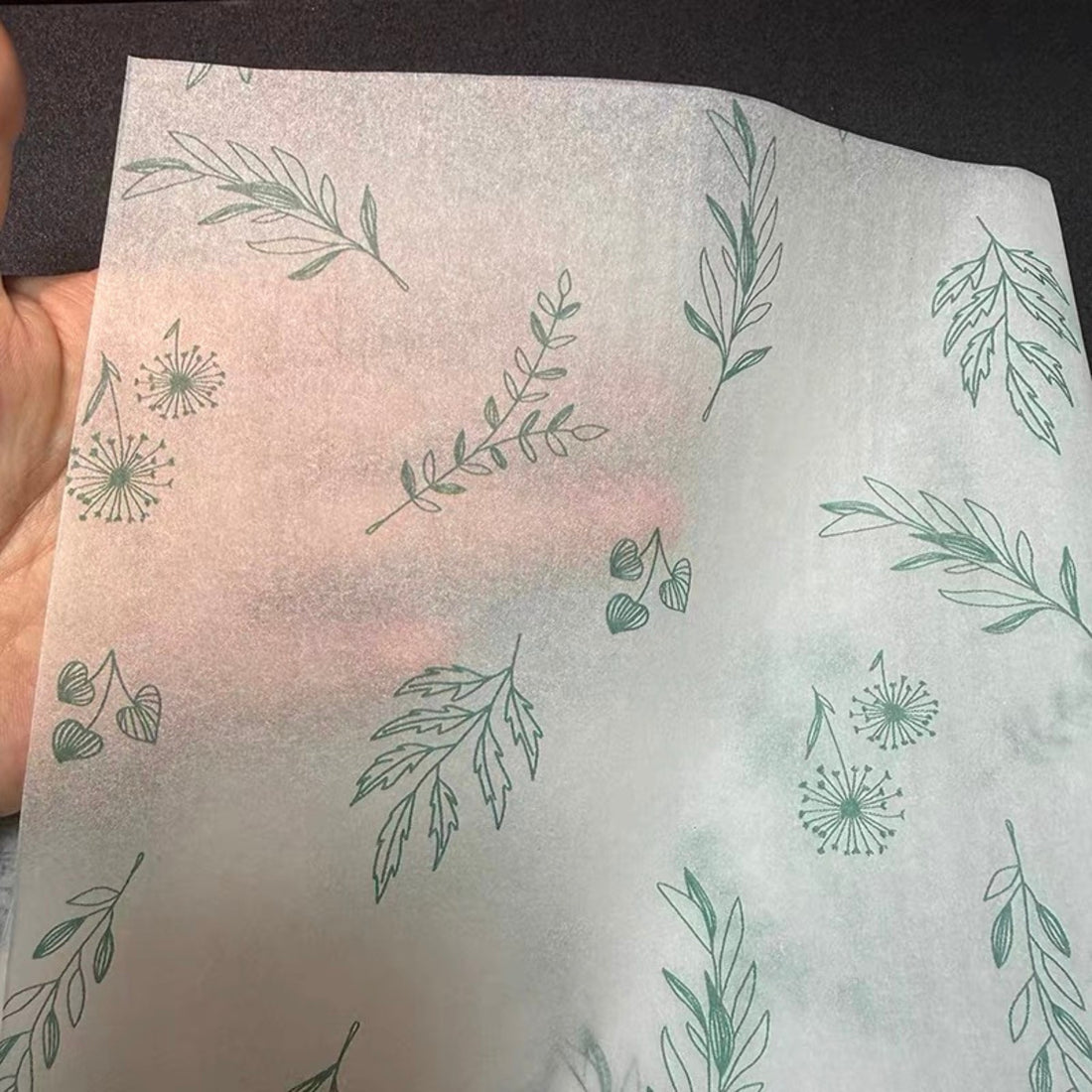 Sheer 17gsm custom printed tissue paper held up to show its soft translucency