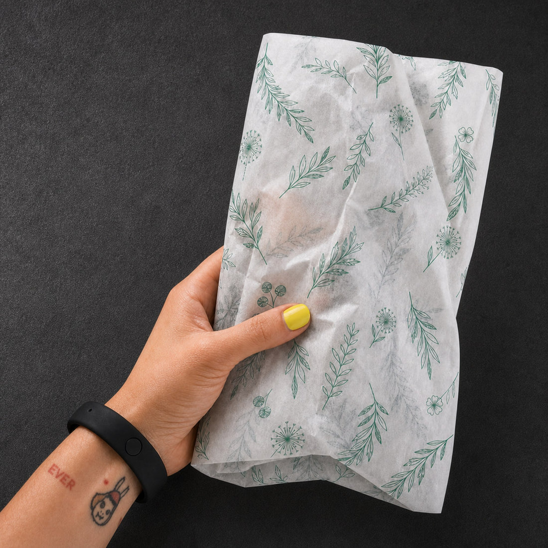 Hand holding a package wrapped in botanical custom printed tissue paper