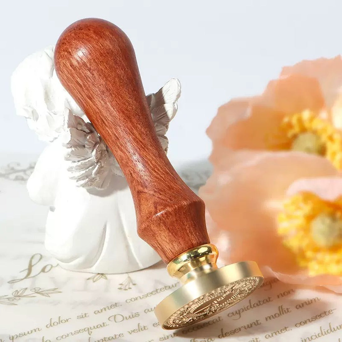 A custom wax seal stamp with a rosewood handle and brass die resting on a sealed letter