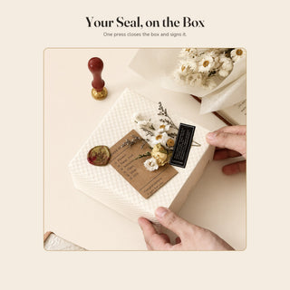 A wax seal closing a white gift box with a kraft tag, sealed with a custom brass stamp