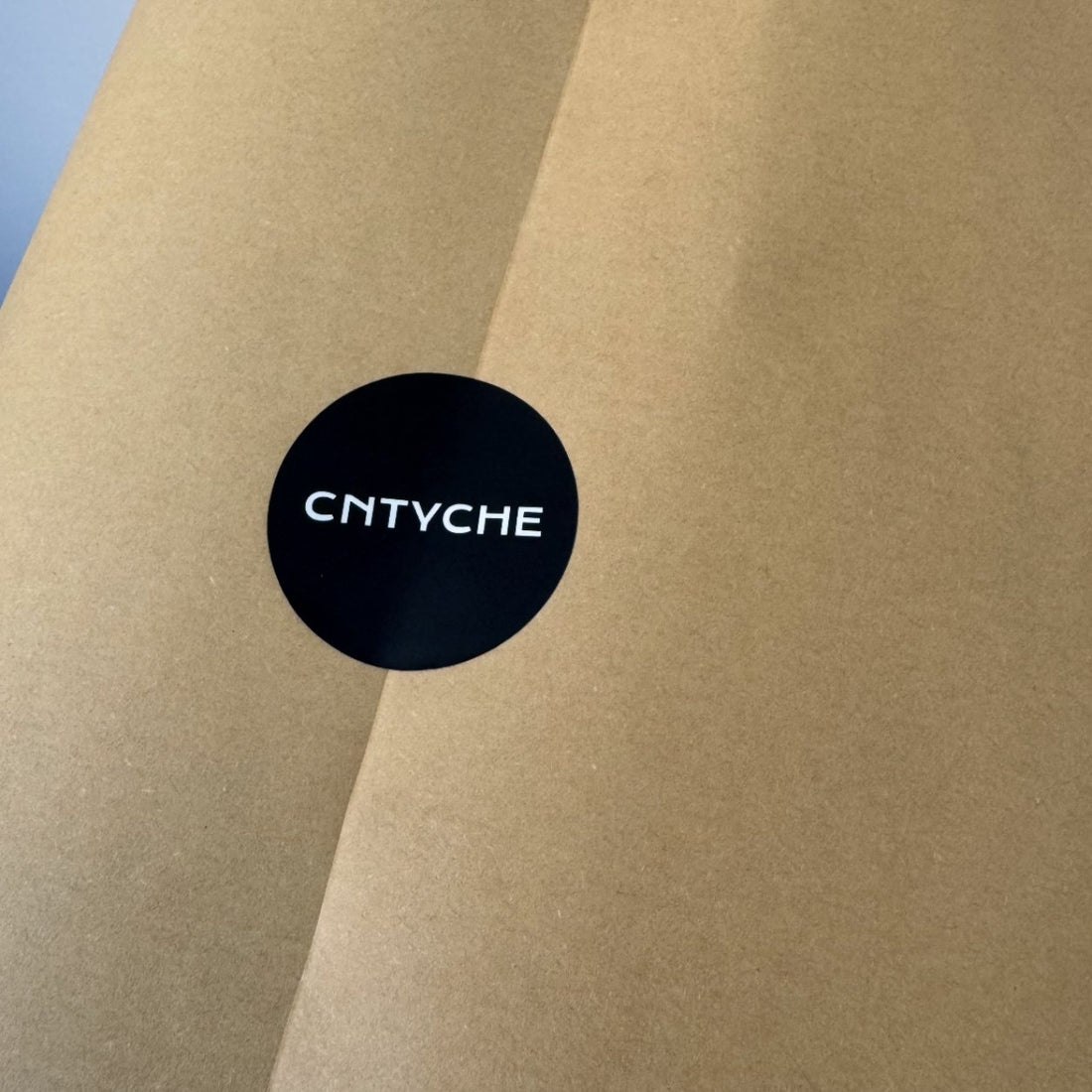 Black matte paper circle sticker with a minimalist logo on kraft paper, smooth no-glare matte finish