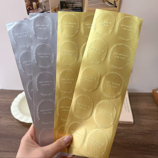 Hand holding gold and silver brushed metallic sticker strips with round labels, metallic finishes