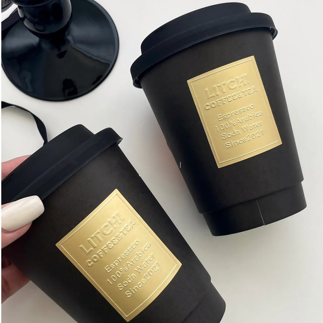 Black coffee cups with matte gold embossed metallic labels, raised emboss on matte gold foil