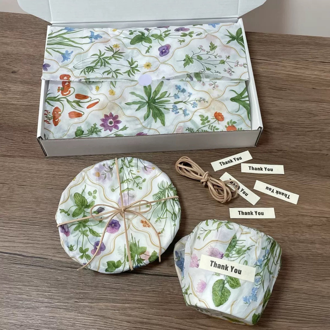Botanical printed tissue paper lining a white mailer box with wrapped items