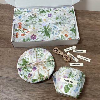 Botanical printed tissue paper lining a white mailer box with wrapped items