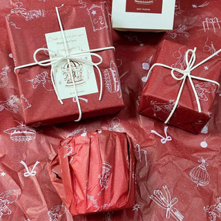 Red holiday tissue paper with white line-art motifs wrapping gifts