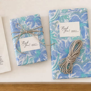 Gifts wrapped in blue floral tissue paper with Thank You cards and twine