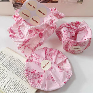 Items wrapped in pink patterned tissue paper and sealed with Thank You stickers