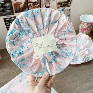 A bundle wrapped in pink patterned tissue paper with a Thank You card