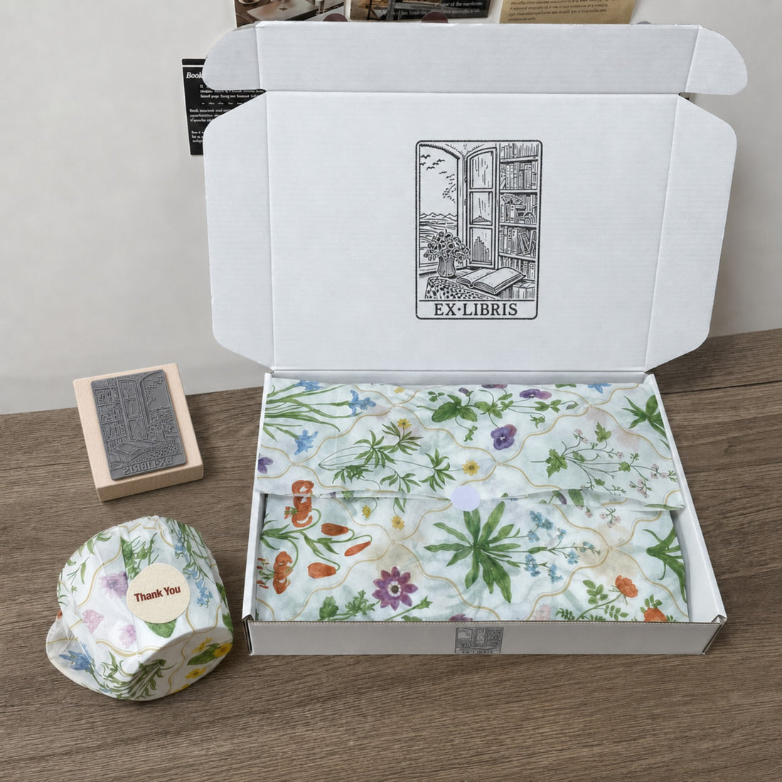 A white mailer box stamped with a logo, lined with printed tissue and sealed with a Thank You sticker