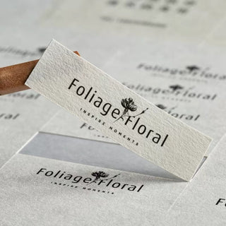 White textured paper label with a full-color printed floral logo, fine felt paper texture