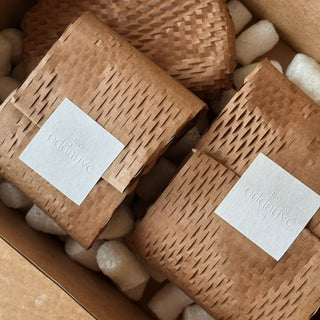 Woven gift boxes with white textured paper labels, embossed branded packaging